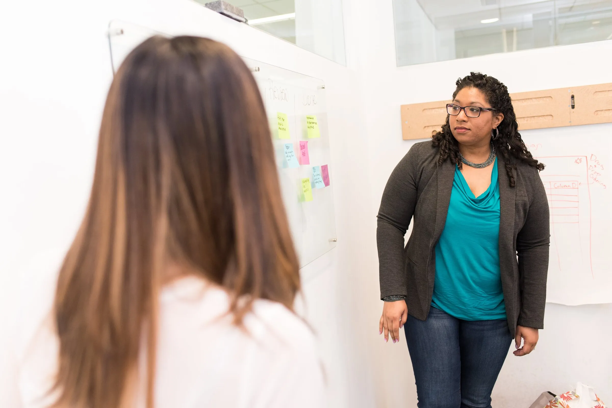 A facilitator at a whiteboard covered in sticky notes, talking to a participant