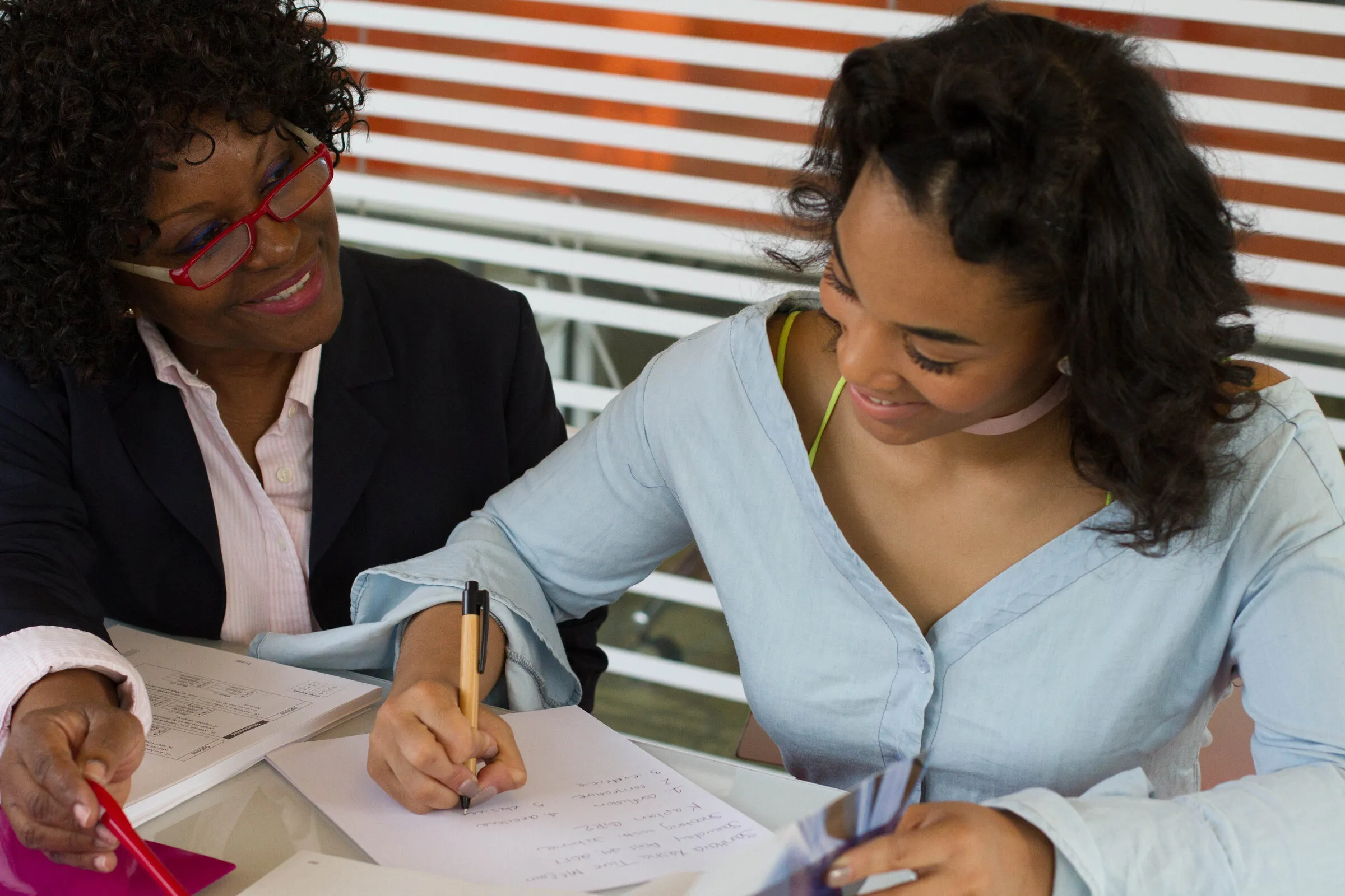 A mentor and a young woman working through an application together at a table