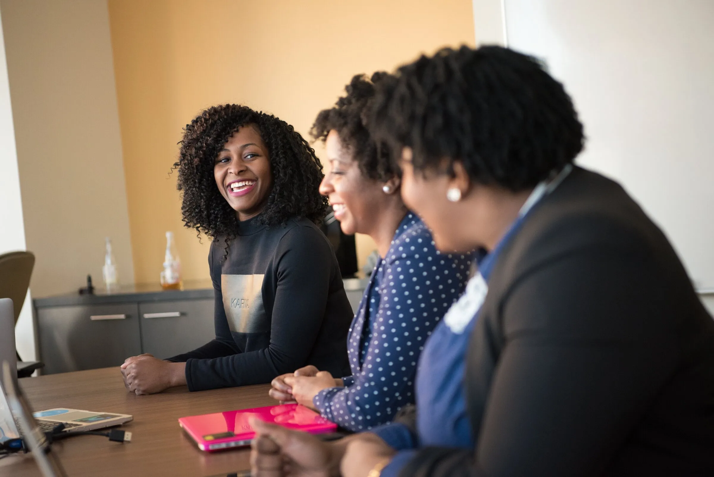 Three women at a boardroom table, mid conversation