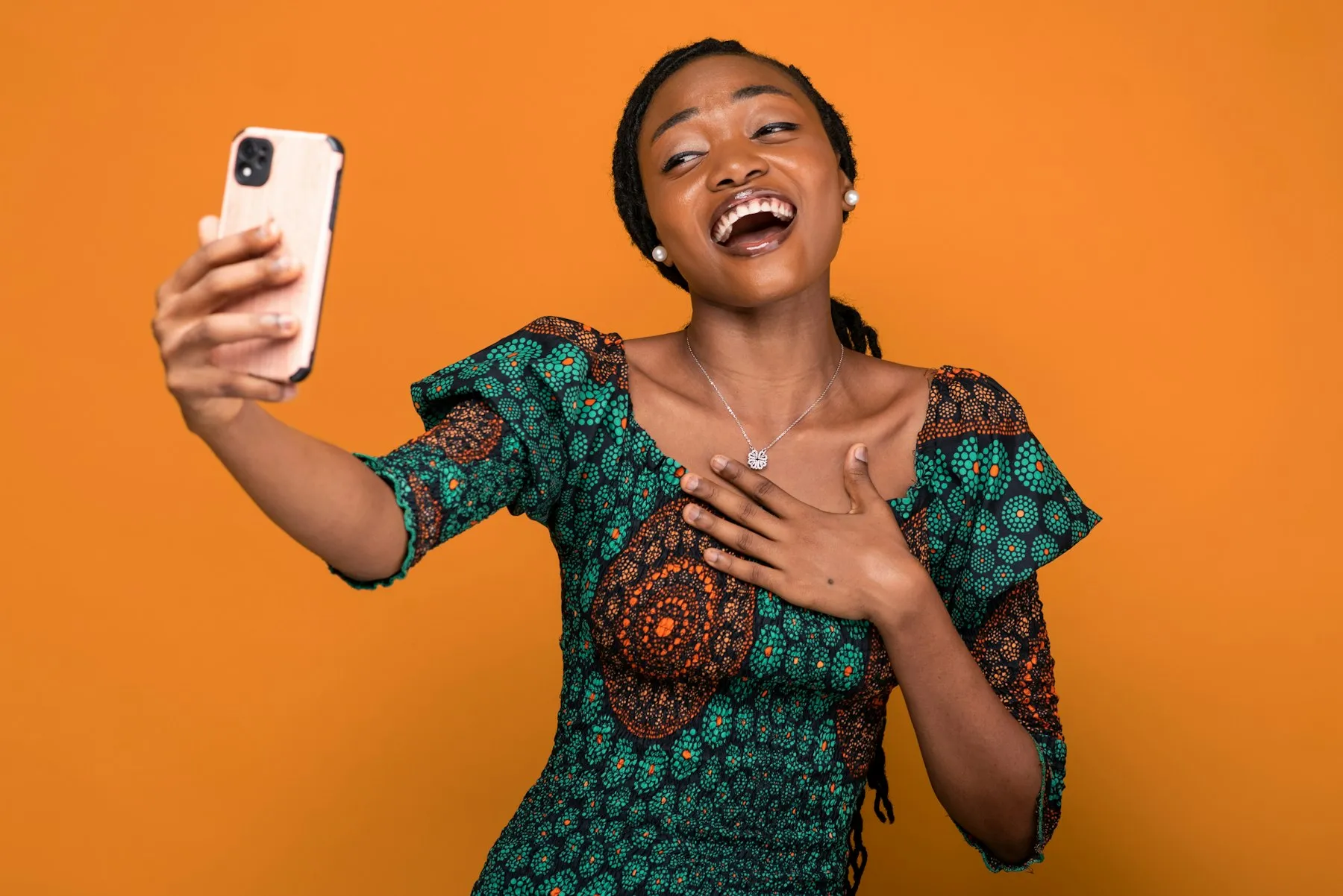 A young woman laughing as she records herself on her phone