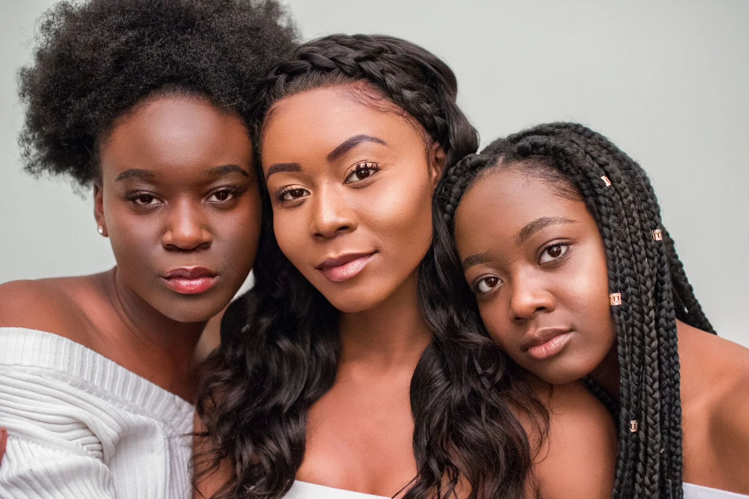 Three young women standing close together, looking straight at the camera