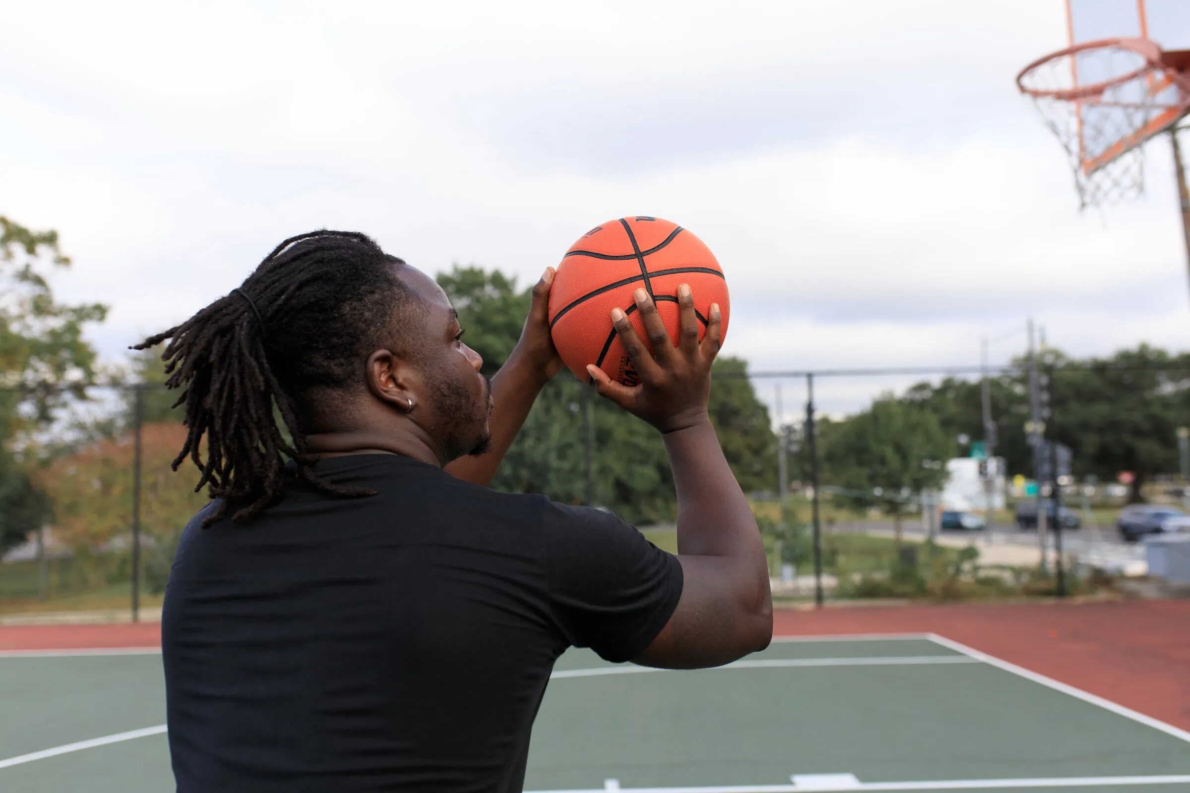 A young man lining up a shot on an outdoor basketball court